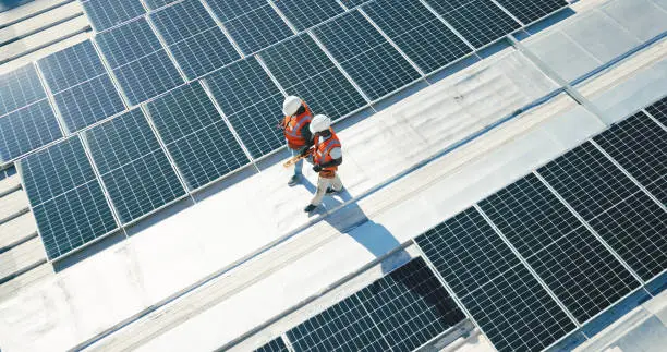 Renewable energy, solar panels and team walking on roof planning for inspection at sustainable business. Engineering, sustainability and photovoltaic power on rooftop, men in electricity maintenance.
