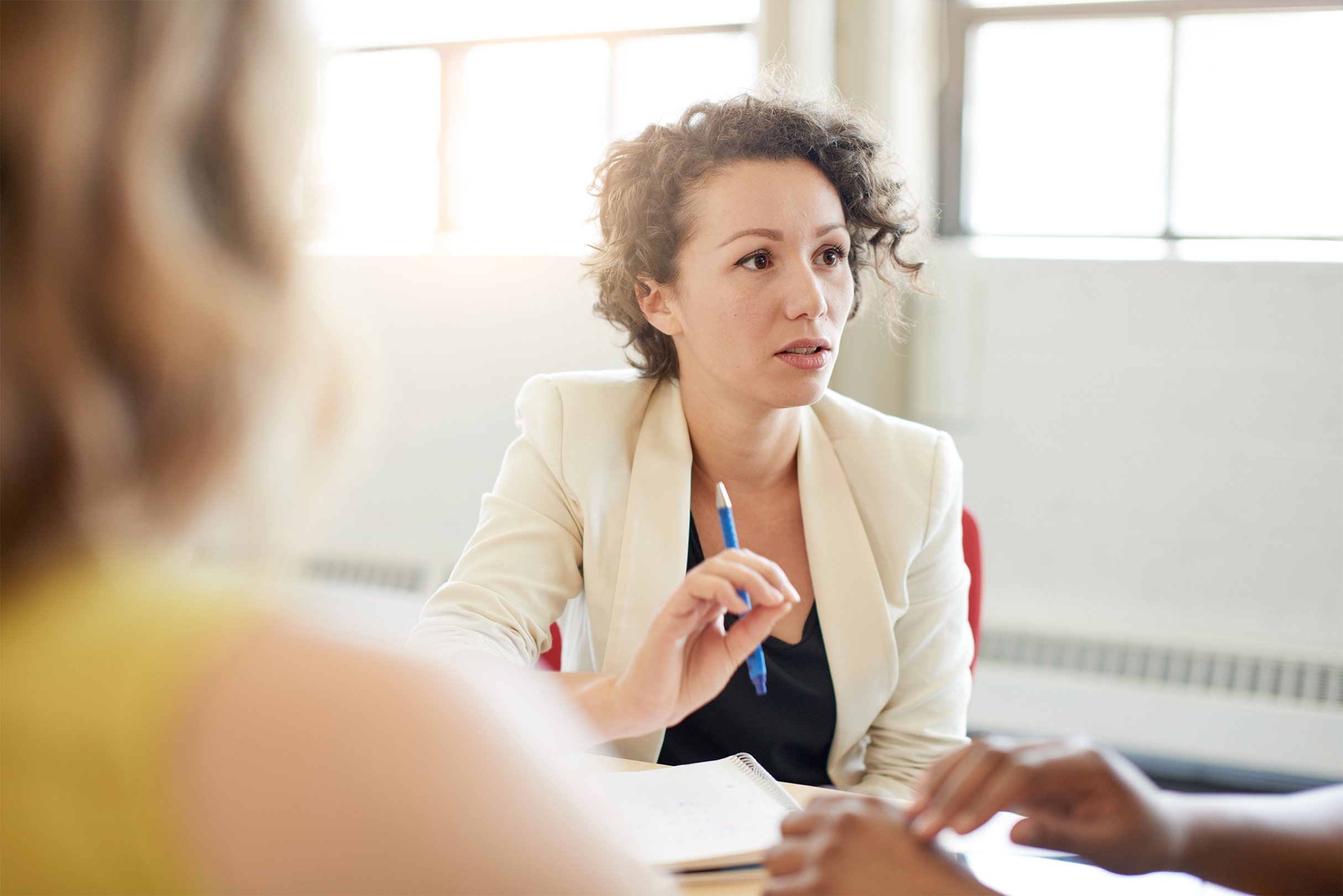 Candid picture of a female boss and business team collaborating. Filtered serie with light flares, bokeh, warm sunny tones.